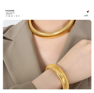Detail of 18K gold-plated Tubogas choker and chunky bracelet set on a blazer