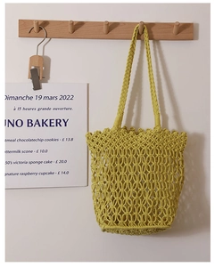 Detail of hollow macrame knot texture on cotton woven shoulder bag in mustard yellow