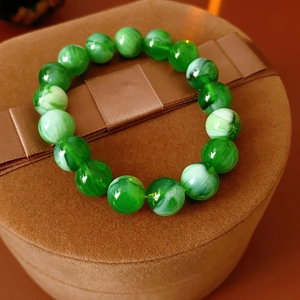Detail shot of green translucent beaded bracelet with cloudy texture on brown velvet display
