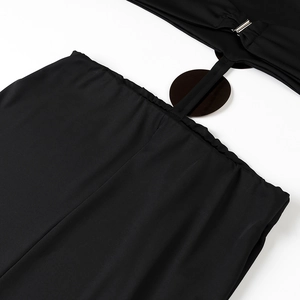 Detail shot of black beach dress featuring side cut-outs and metallic buckle hardware