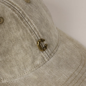 Beige washed cotton baseball cap with vintage C-shaped metal emblem decoration