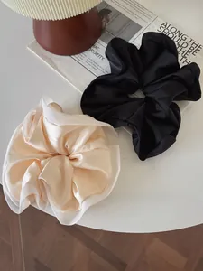 Detailed macro of black and champagne satin scrunchies with sheer organza edges on a table