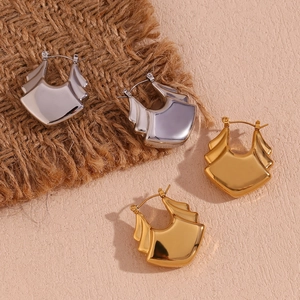 Detailed close-up of chunky irregular gold and silver tiered fan-shaped earrings on burlap