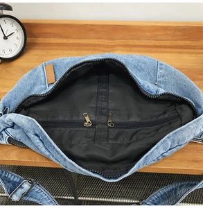 Detail shot of the denim crossbody bag showing the inner zipper pocket and black lining