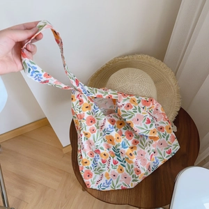 Detail of floral cotton tote bag with colorful watercolor patterns on a wooden stool