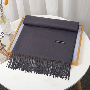 Detailed texture of dark grey cashmere scarf with elegant fringe and quality label
