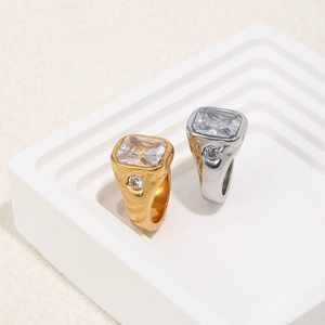 Detailed view of gold and silver steel rings with rectangular cubic zirconia on white steps