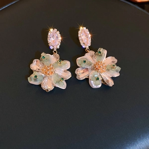 Macro detail of woven crystal flower earrings with silver needles and gold accents
