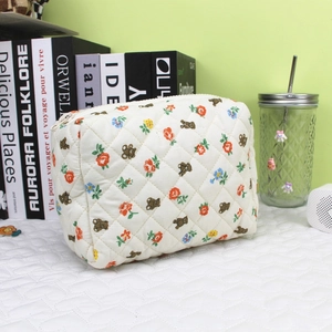 Detailed view of cream quilted cosmetic bag with cute cartoon bears and colorful floral patterns