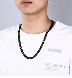 Close-up of a men's thick black stainless steel Cuban link chain worn by a male model