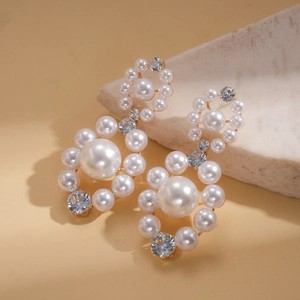 Macro detail of elegant gold-tone pearl earrings with sparkling round cubic zirconia
