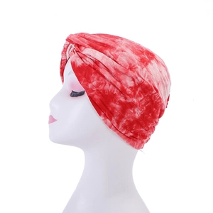 Detailed side view of tie-dye knotted turban hat in red and white on a model head