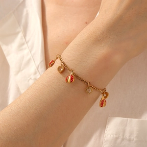 Gold ladybug and CZ heart charm bracelet on wrist, elegant stainless steel jewelry for women