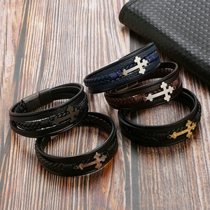 Detailed view of multilayer leather bracelets with metal crosses on a rustic wooden background