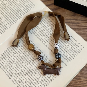 Silk scrunchie necklace with dachshund pendant and animal print beads on an open book