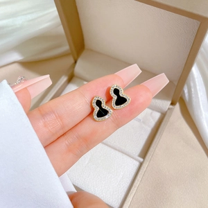 Close-up of gold titanium steel gourd earrings with black enamel and white crystals