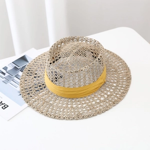 Handwoven seagrass sun hat with yellow ribbon detail on a clean white surface