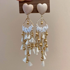 Detail showing bohemian tassel earrings with wooden heart bead and white fringe design