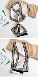 Close-up of champagne long silk scarf with navy geometric borders on wooden tray