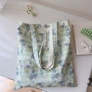 Close-up of floral elephant print canvas tote bag with woven label and soft lighting