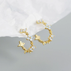 Detailed macro view of gold C-shaped earrings with opal-like floral petals for women