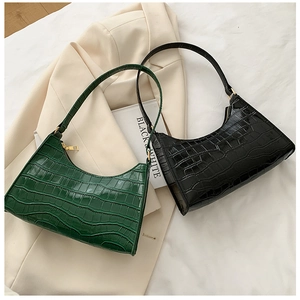 Detail of crocodile pattern texture on green and black faux leather baguette bags