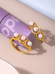 Macro shot of gold vintage carved rings with three inlaid white pearls and zircon accents