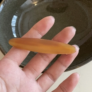 Macro detail of a translucent amber acetate hair clip with a smooth glossy resin finish