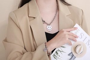 Silver stainless steel chain necklace and bracelet set with smiley face charms on model