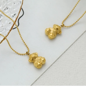 Close-up of golden 3D geometric bear pendants on bead chains with quilted texture