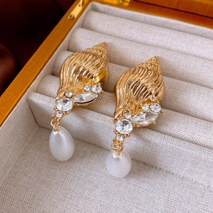 Macro detail of vintage conch earrings with sparkling rhinestones and pearl drops