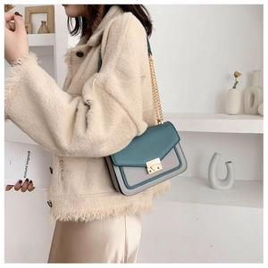 Detail view of teal and grey color-block crossbody bag with gold chain strap and lock