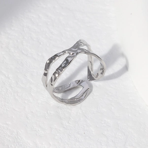 Macro detail of irregular silver hammer-textured stainless steel open ring on white background