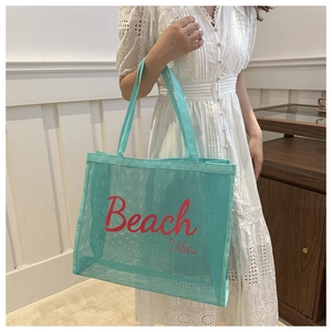 Detail of mint green mesh beach tote bag featuring red Beach Vibes text and nylon texture