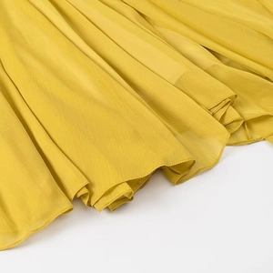 Detail des gelben Chiffon-Midi-Rock-Saums mit feinen Plissee-Falten und Textur