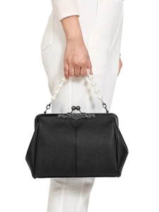 Detail view of vintage kiss lock closure and white pearl handle on black leather handbag