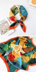 Detailed close-up of a silk square scarf with colorful artistic gingko leaf patterns
