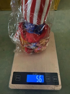 Close-up of Independence Day gnome doll on a digital scale showing a weight of 56 grams