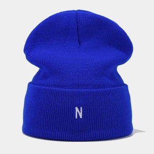 Detailed close-up of blue knitted beanie featuring a white embroidered letter N on the cuff