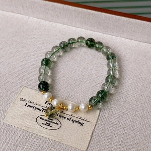 Detail of white crystal bracelet with green inclusions, pearls and gold spacers