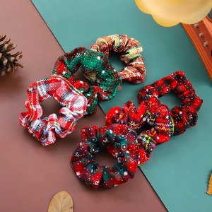Set of four Christmas plaid scrunchies with snowflake patterns on a festive backdrop