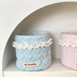 Detailed view of quilted storage baskets with lace trim and polka dot lining in a soft setup