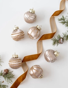 Detail of silk-wrapped champagne gold Christmas ornaments with beads and glitter accents