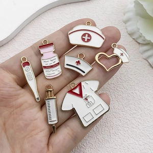 Nurse medical enamel pendant set featuring syringe and heart charms on palm display