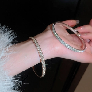 Close-up of elegant gold and silver paved rhinestone bangles worn on a model wrist