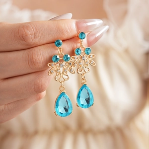 Close-up of vintage gold earrings with blue teardrop gemstones and floral metalwork