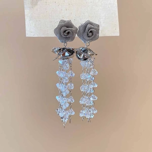 Macro detail of silver rose earrings featuring delicate mesh petals and crystal tassels
