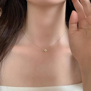 Close-up of gold clover pendant with small white zircon stones on woman's neckline