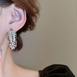 Gros plan des boucles d'oreilles feuille en argent serties de zircons scintillants