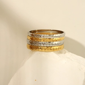 Detail of 18k gold and silver diamond-cut lattice texture bracelets on white stone